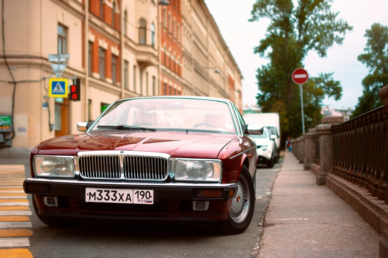 a red vintage car is parked on a city street