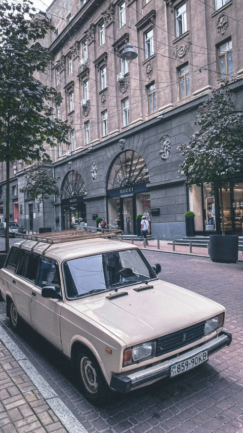 an old car parked on a side walk next to a tall building