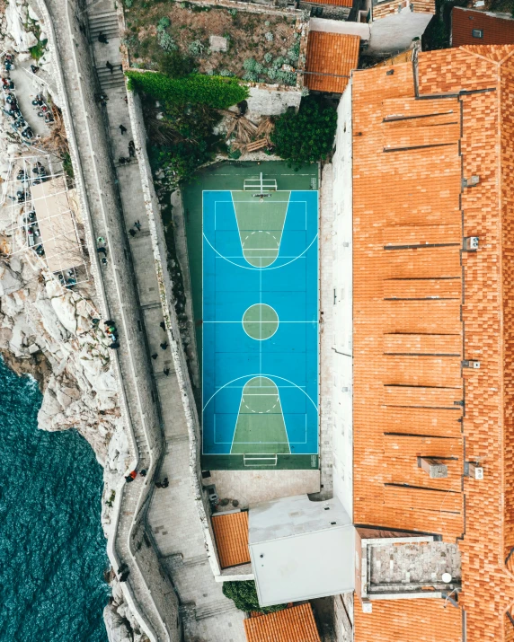 an aerial view of a basketball court and water in a parking lot