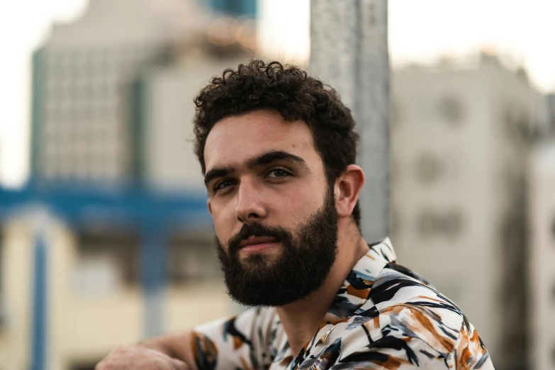 a man with a beard is standing by a street pole