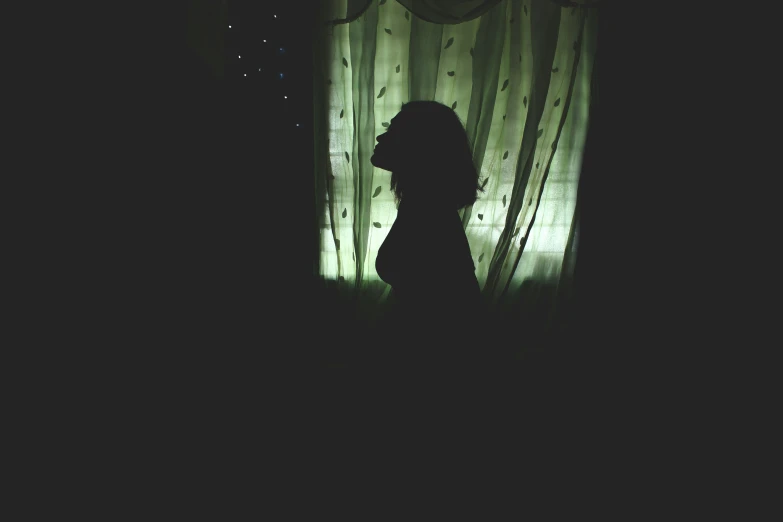 a black and white po of a silhouette against a curtain