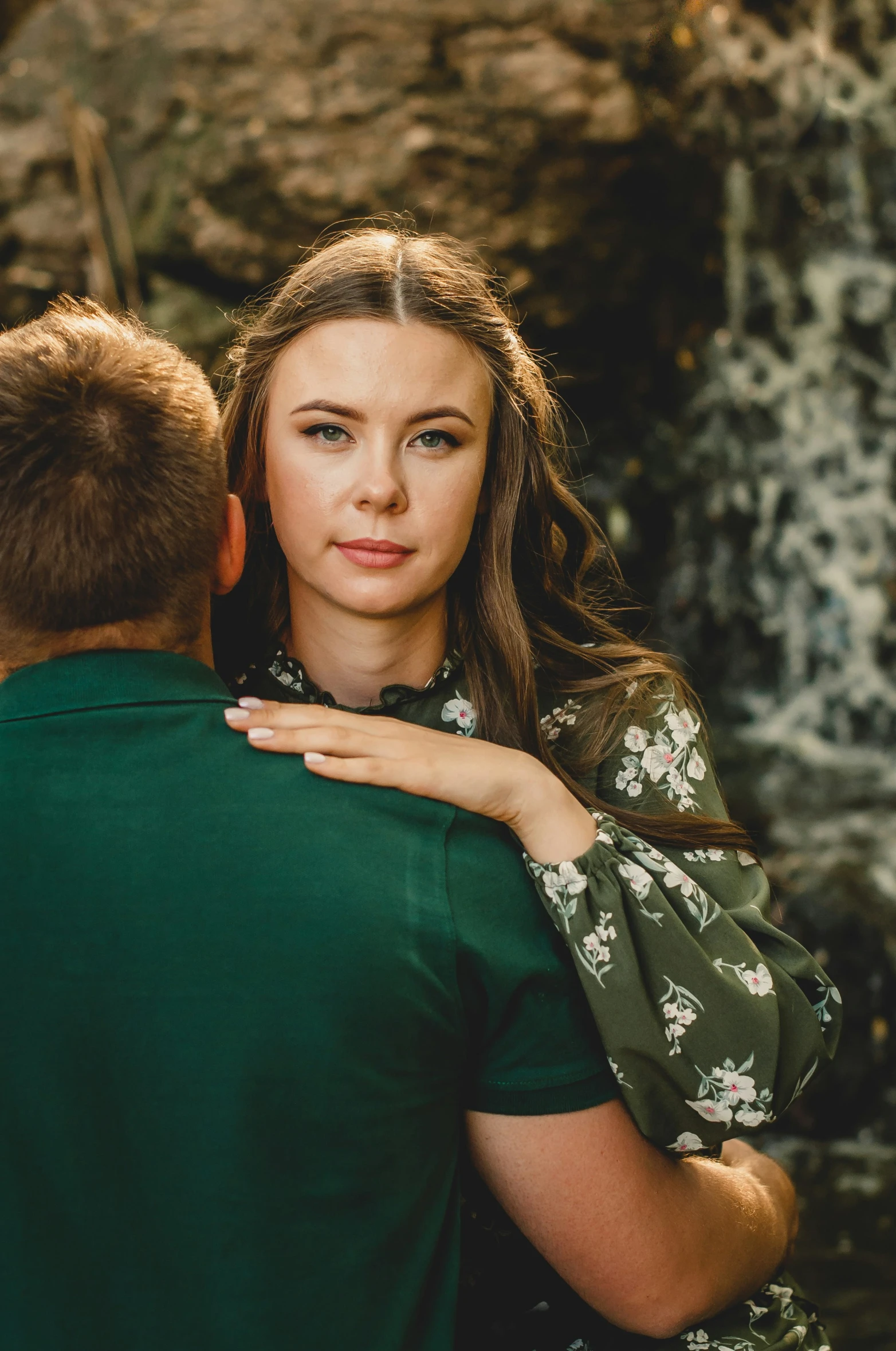 the man holds his girl in his arms near a waterfall