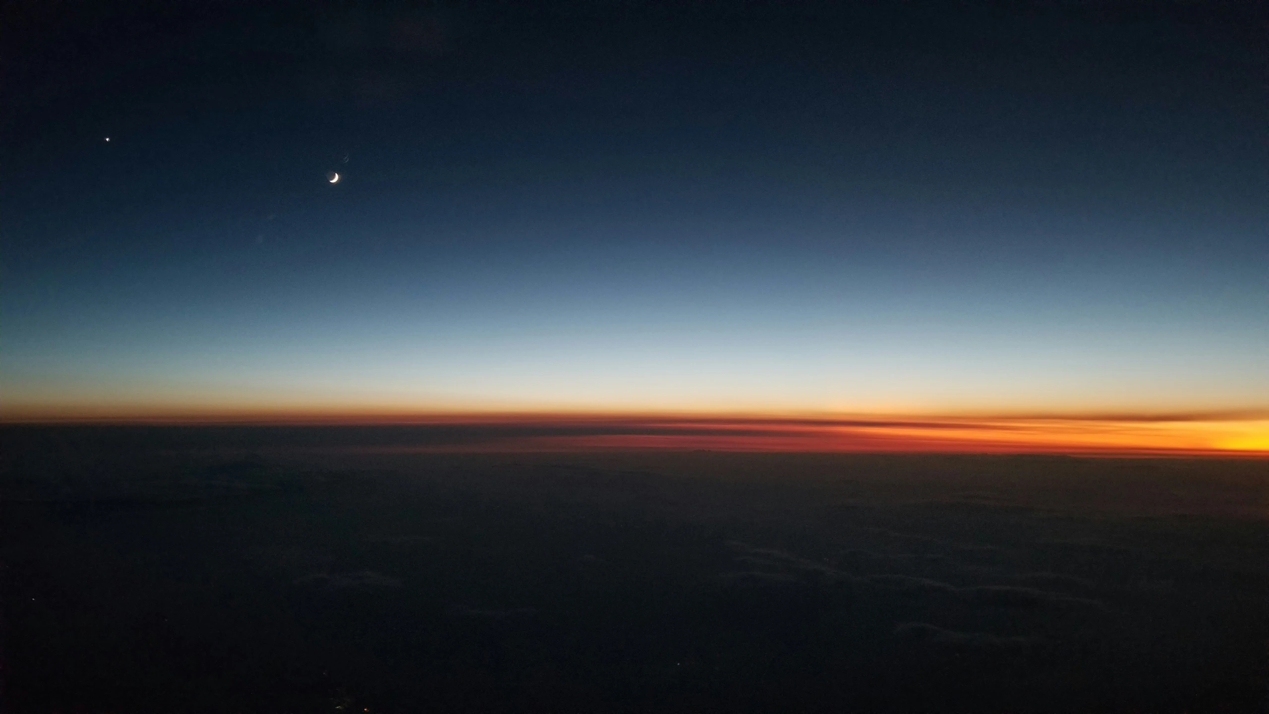 the sunset and the moon are seen over an airplane wing