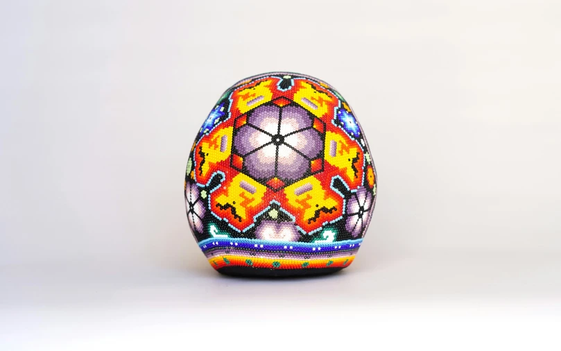 an elaborate colored decorated egg against a white background