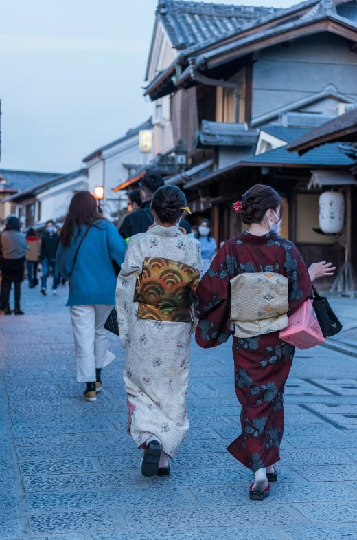 two women in kimonos are walking down the sidewalk