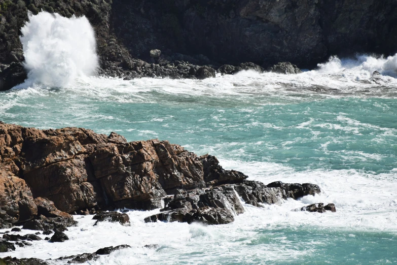 waves crashing onto the rocks of a cliff near the beach