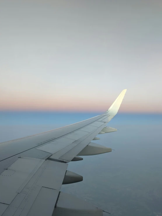 the wing of an airplane flying above the ground