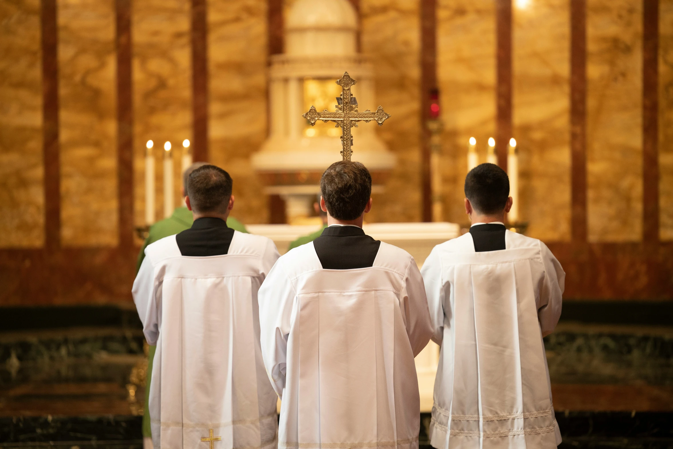 three men in white clothes standing at the alter of a church