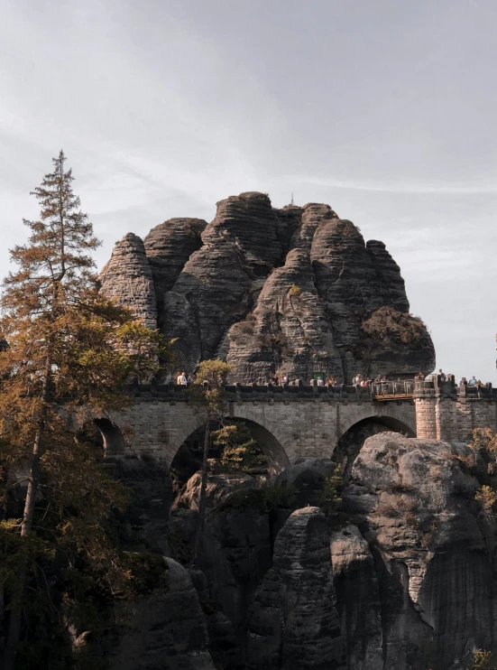 a large stone bridge spanning across a cliff with trees on both sides