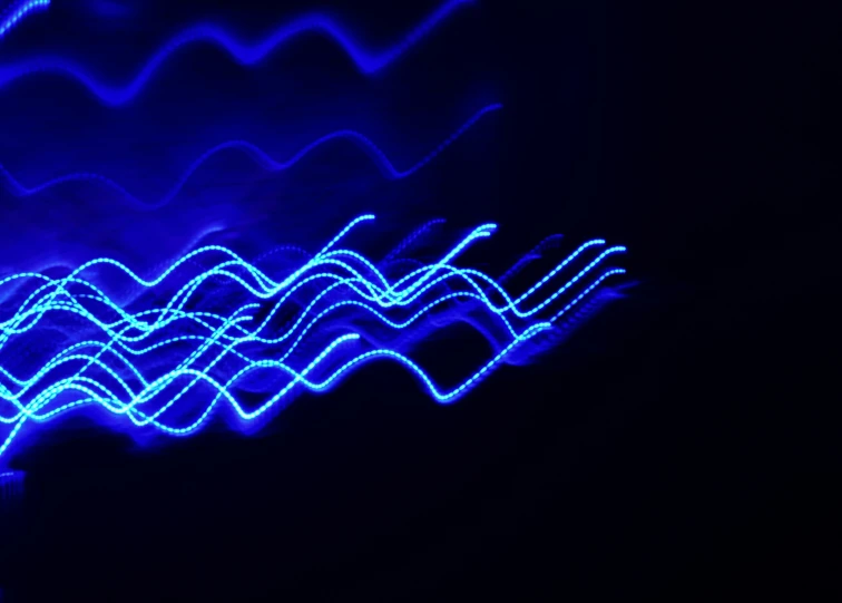a dark wall has blue light that is in the shape of waves