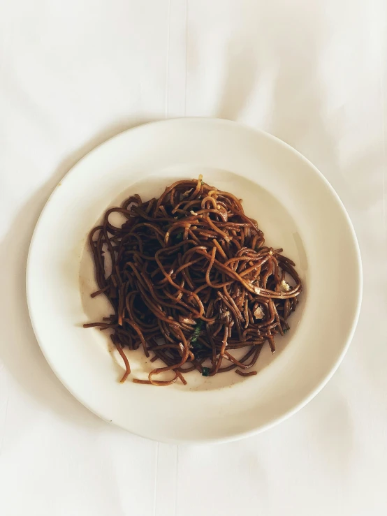 a plate with noodles and an egg on a white table cloth