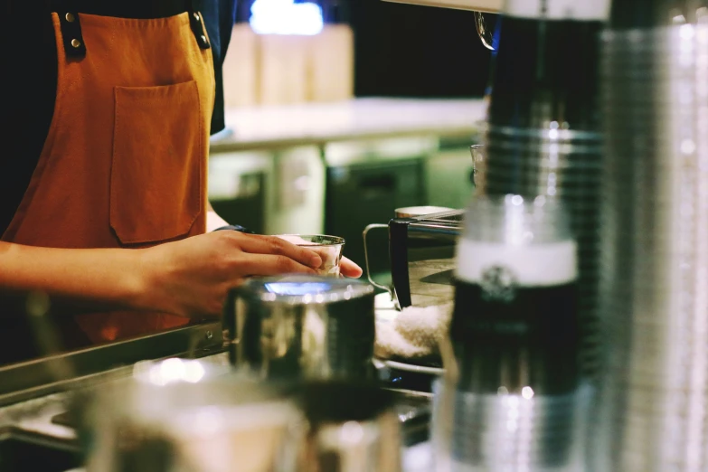 someone in apron and orange shirt preparing food at a restaurant