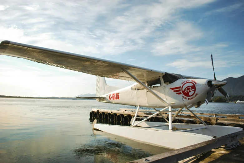 small plane parked by the water on a pier