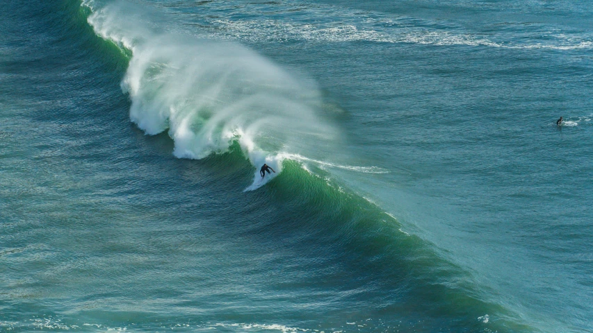 a large wave crashing behind a surfer riding the one wave