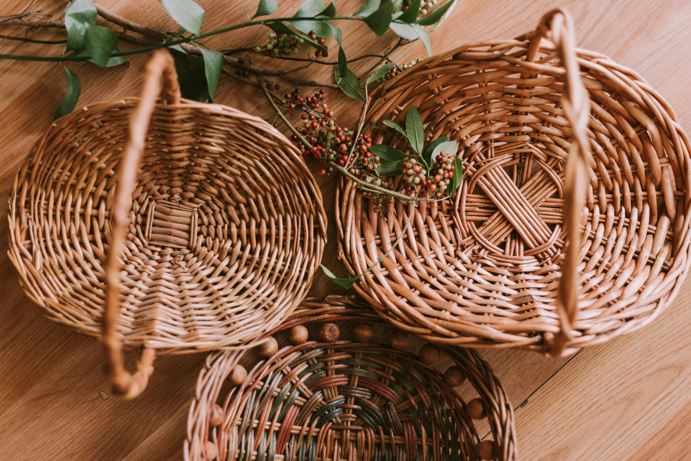 three wicker baskets that are holding berries and greenery