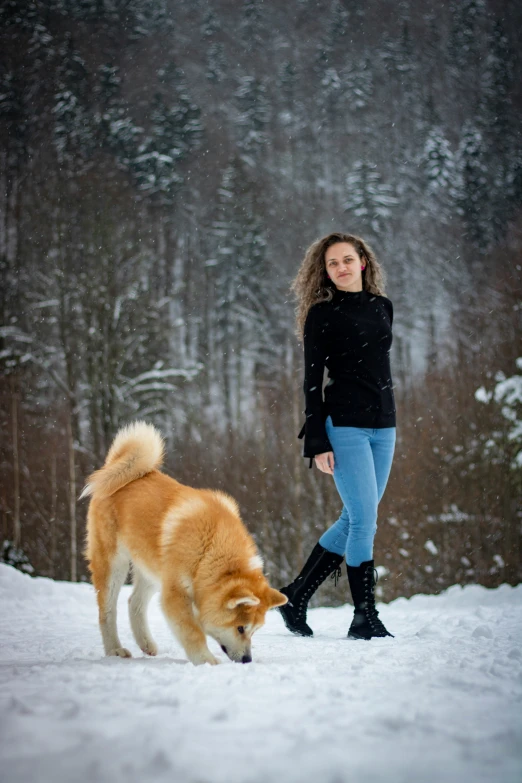 a woman walking along side a dog in the snow