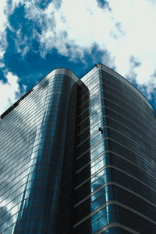 a high rise building is seen against a blue cloudy sky