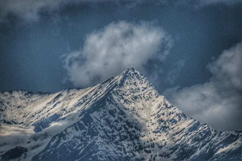 a large mountain covered in snow and cloud formations