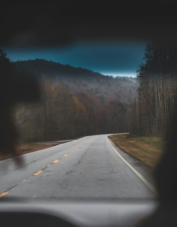 a black car drives down a mountainous road at dusk