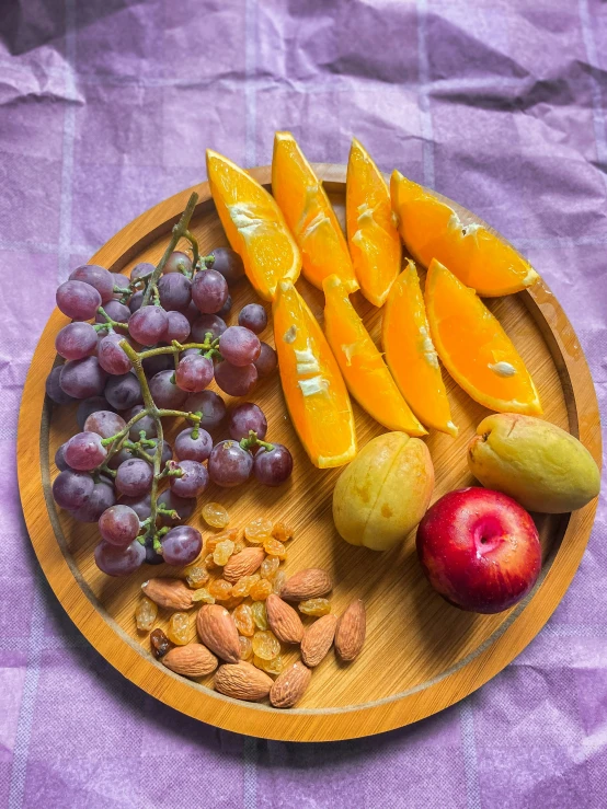 a wooden plate with gs oranges and nuts