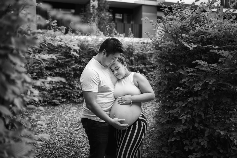 a pregnant couple poses for the camera in front of a building