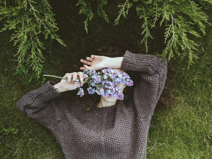 a young woman holding flowers from her arms over her face