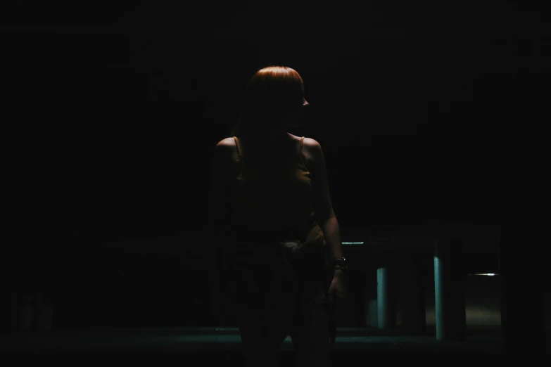 a woman stands alone in the dark at night