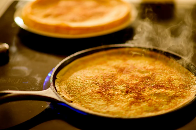 a close up of a frying pan on a stove top with  food cooking