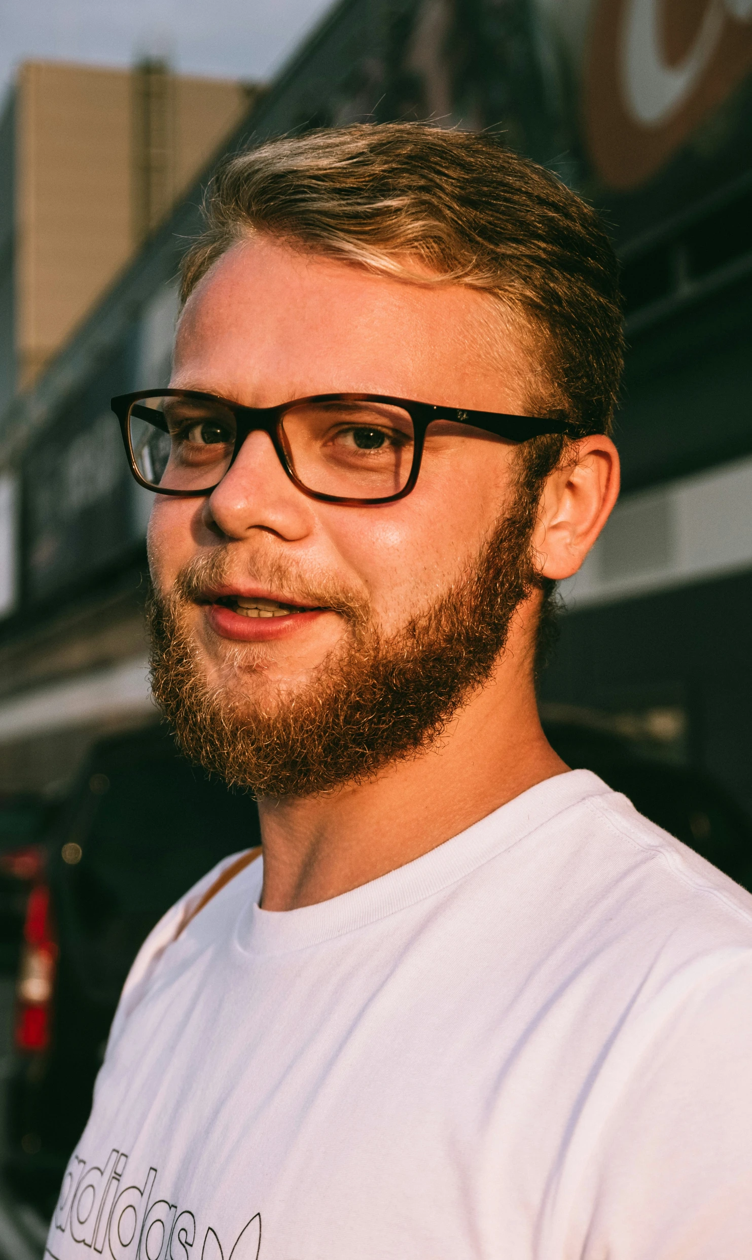 man wearing glasses standing on the sidewalk with a building in the background