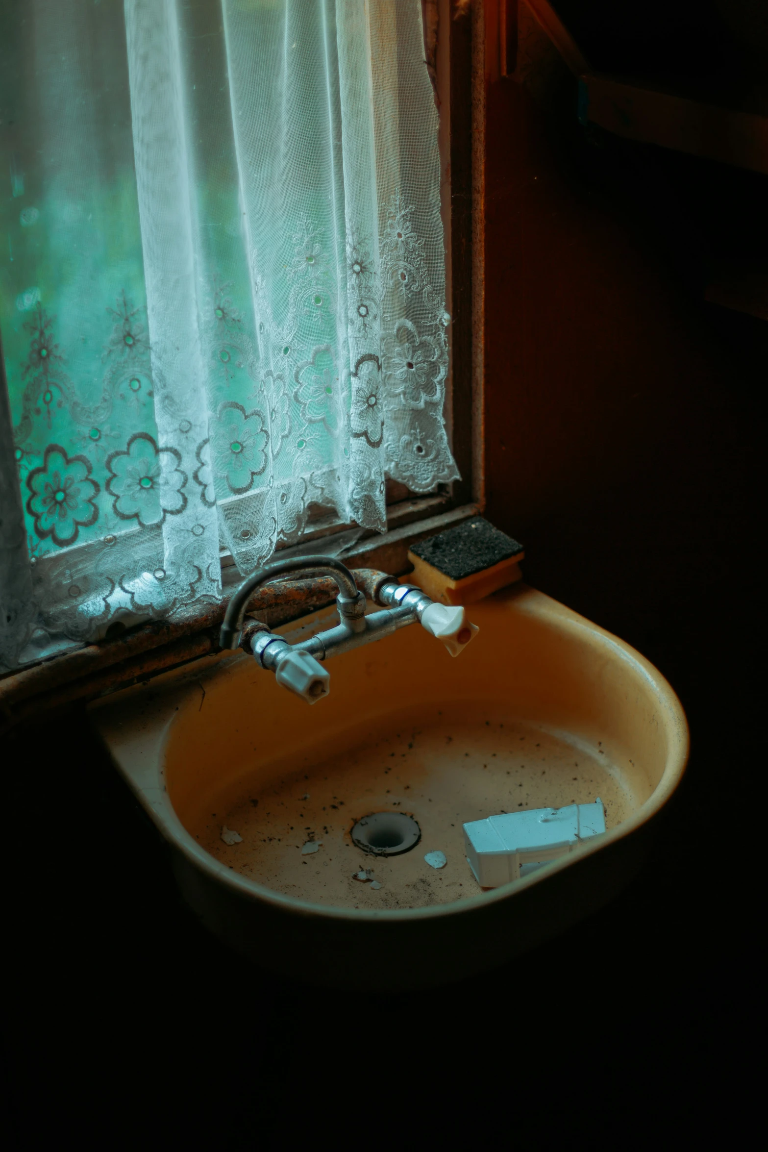 a window covered with curtains next to a yellow sink