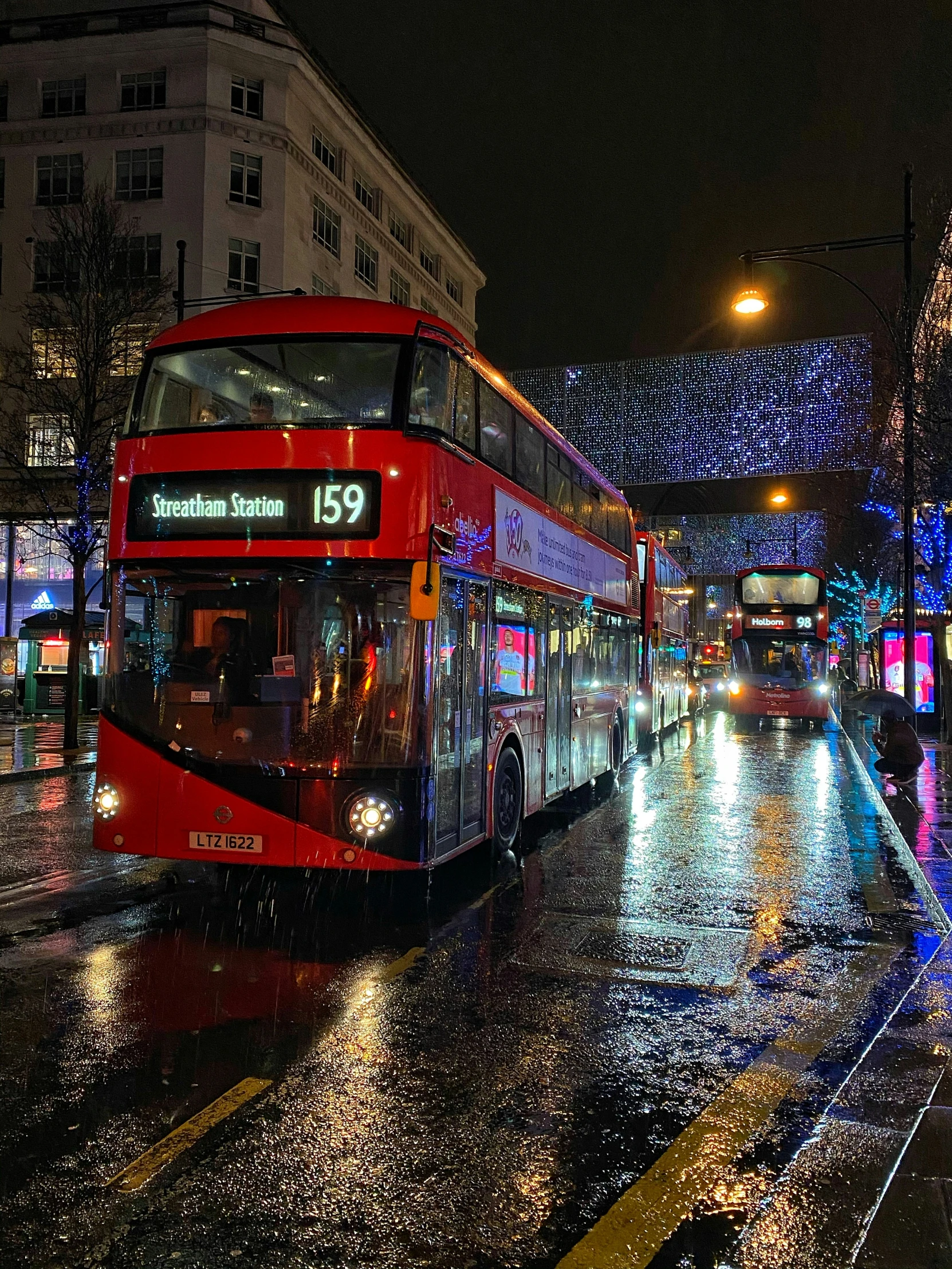 a couple of double decker buses are going down the street at night