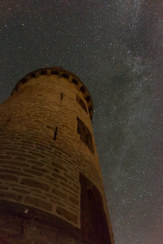 a stone tower in front of the sky filled with stars