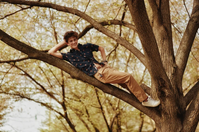 a boy wearing blue and white shoes laying in a tree