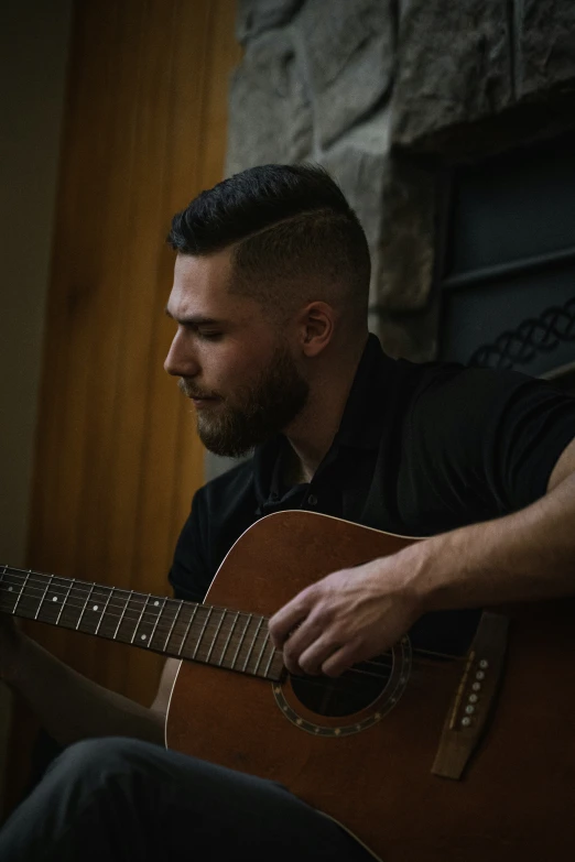 a man sitting down and playing a guitar