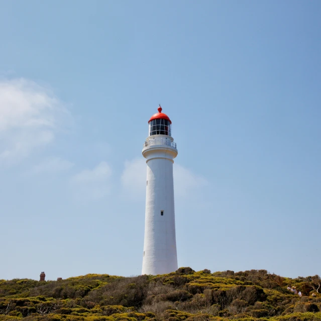 a white and black lighthouse in a blue sky