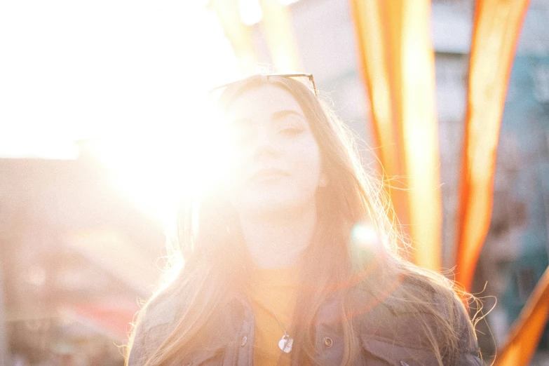 a woman wearing a black jacket with the sun shining behind her