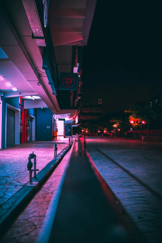 an empty street at night with people walking near it