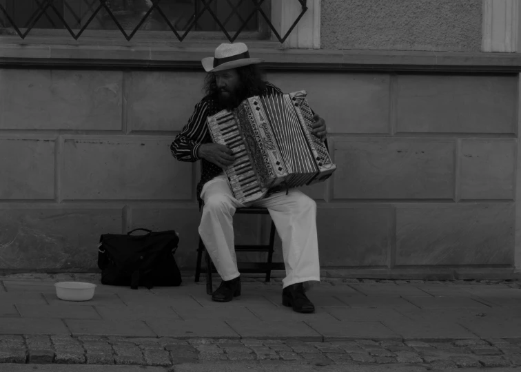 an old man sitting on a stool with an accordion