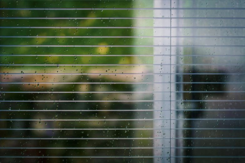 a window with rain falling down and a building in the distance