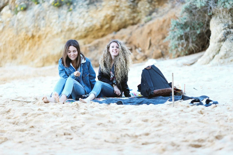 two women are sitting on the sand