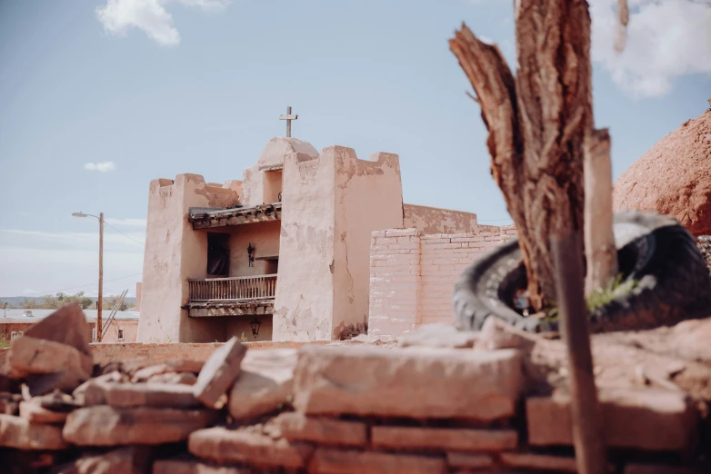 a building with a cross on the roof is in the middle of ruins