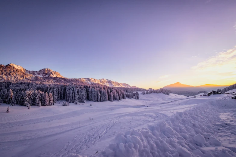 the sun rising over mountains and a group of skiers on them