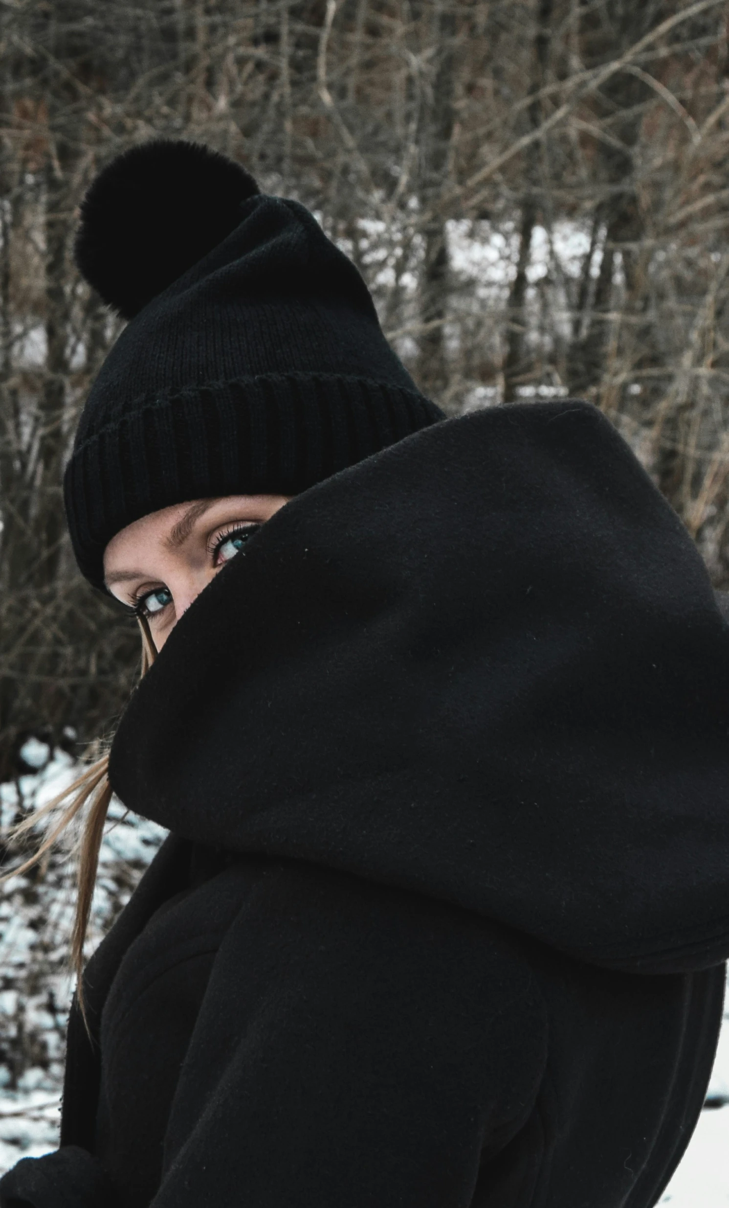 a woman looking in a distance, wearing a black coat and hat