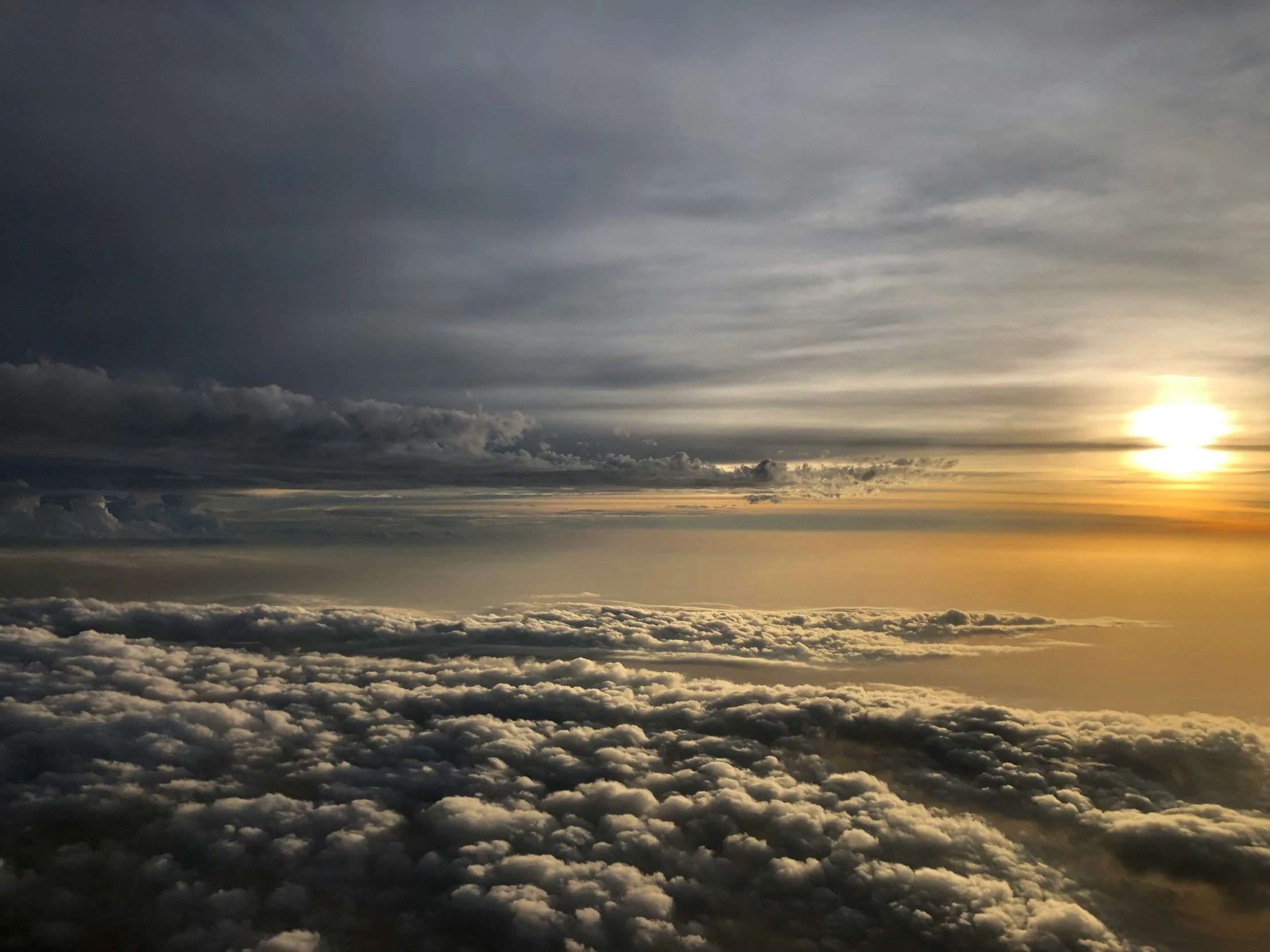 a view of an expanse of clouds and the sun in the distance