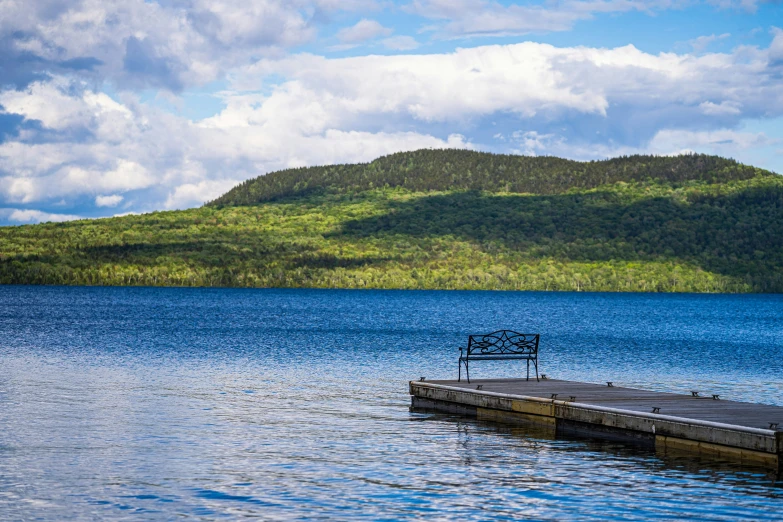 the bench is positioned by the water next to the dock