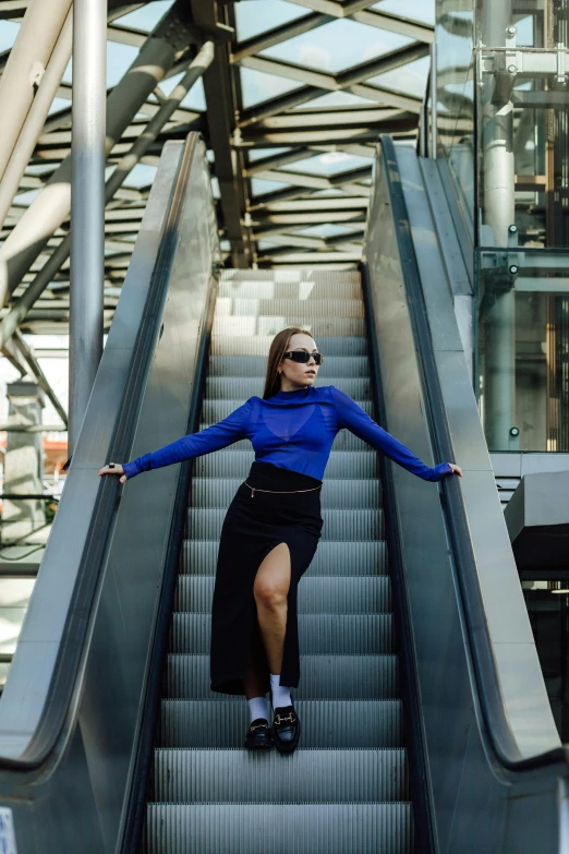 a woman with blue shirt and glasses sliding down an escalator