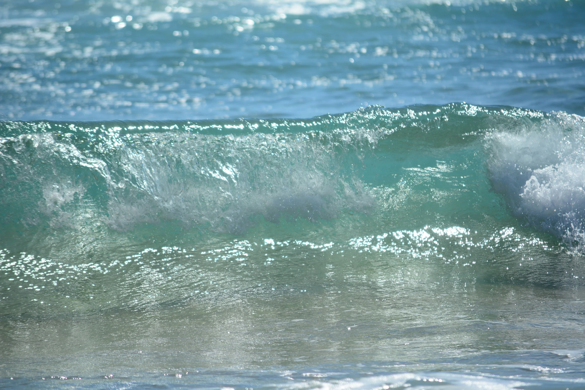 a wave rolls in on the beach and it is blue