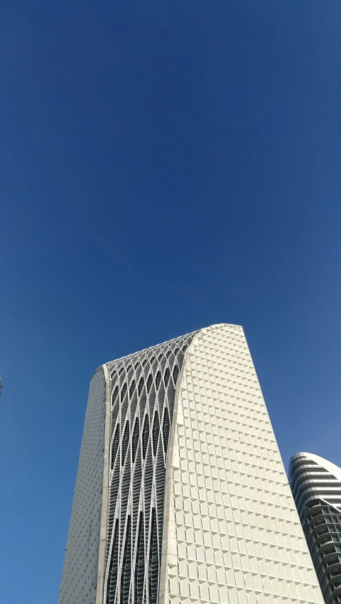 a very tall white building towering above another one