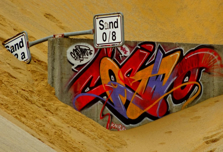 a skateboard ramp with several graffiti and street signs on it