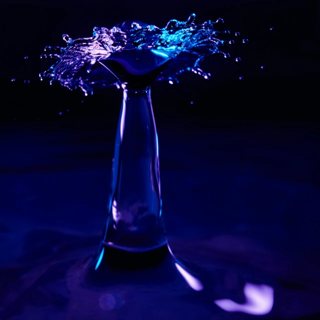 blue light with splashing water on it in a vase